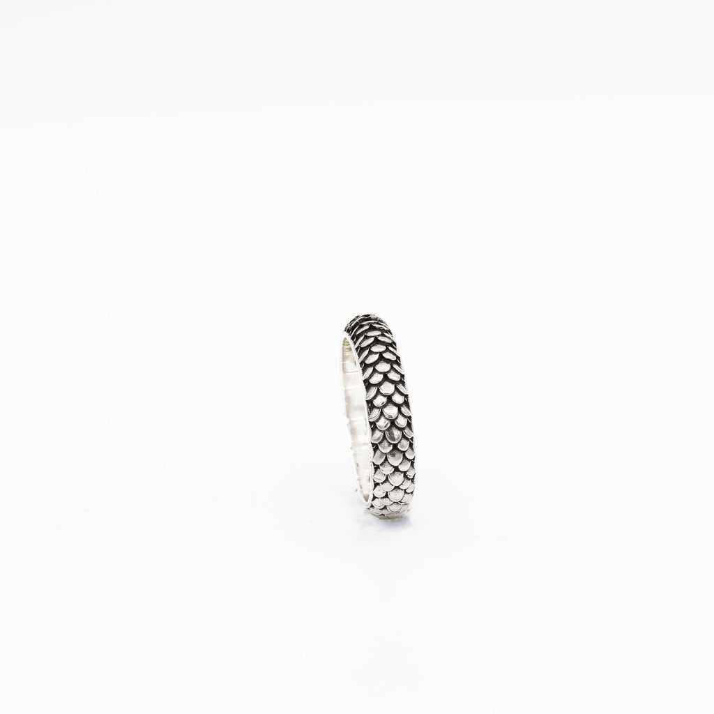 A silver ring with a textured band, featuring the name 'Dragon' engraved on it.