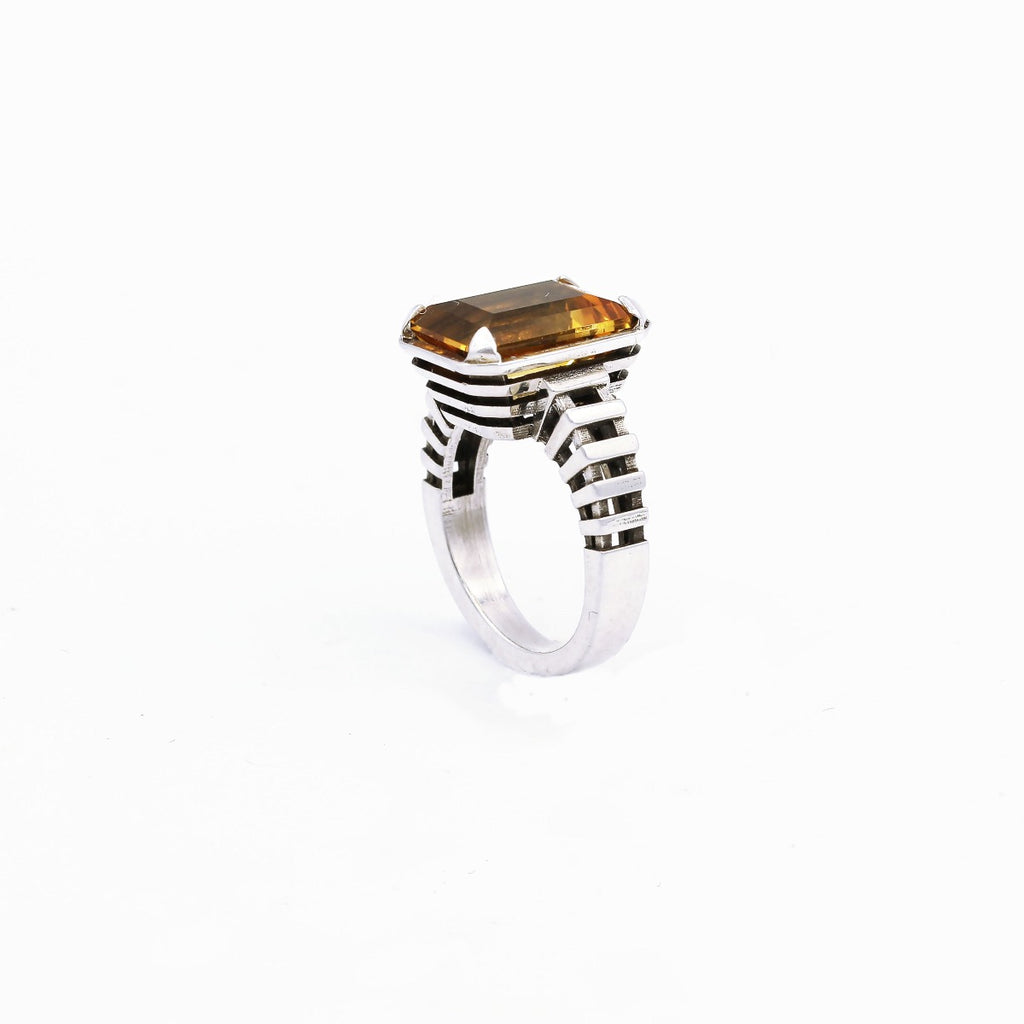 A ring with a large citrine gemstone set in a silver band, with a minimalist design and modern edge.