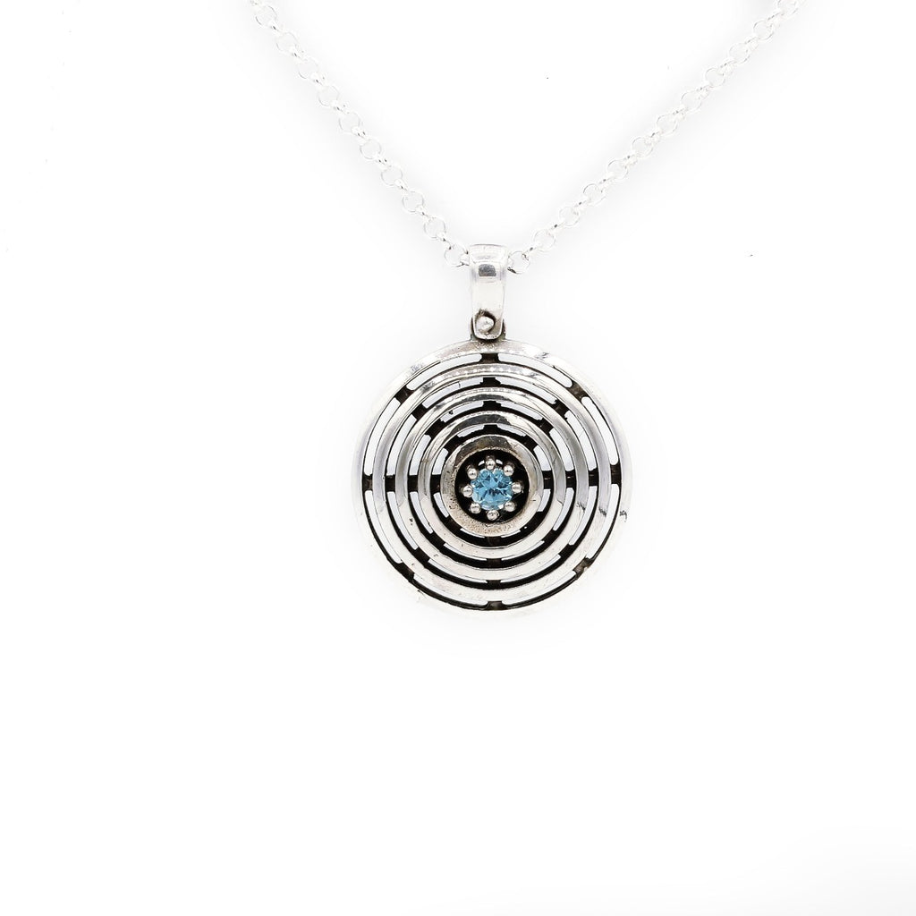 A sterling silver necklace with a blue topaz gemstone pendant featuring a simple interlocked circles design.