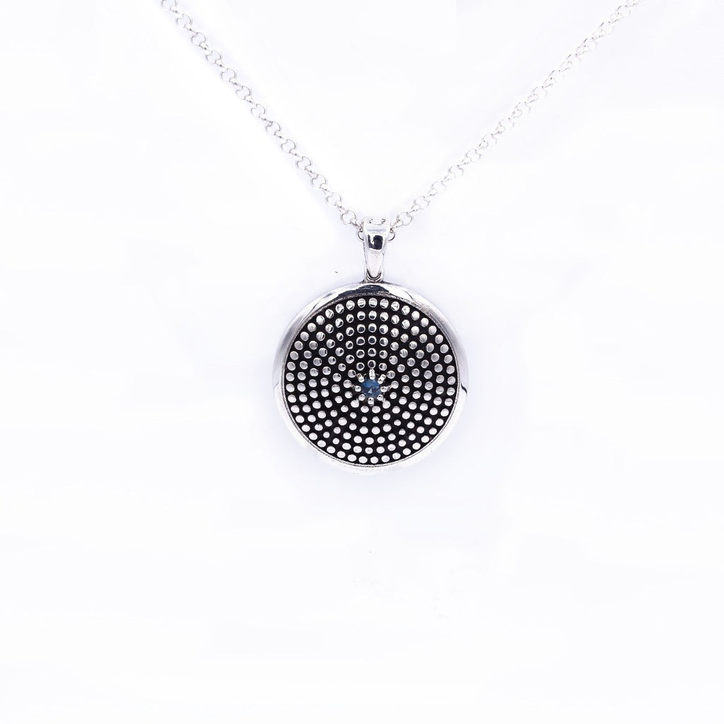 A blue topaz gemstone pendant set in a silver mounting, suspended from a chain.